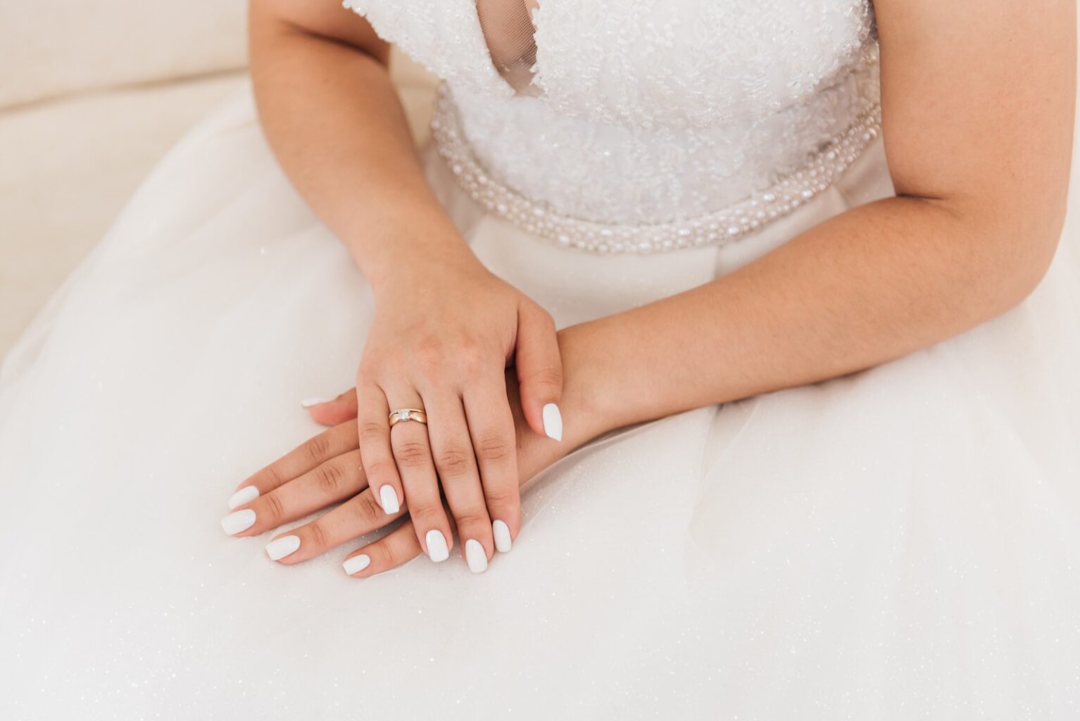 Mujer vestida de novia con un vestido blanco y una manicura blanca